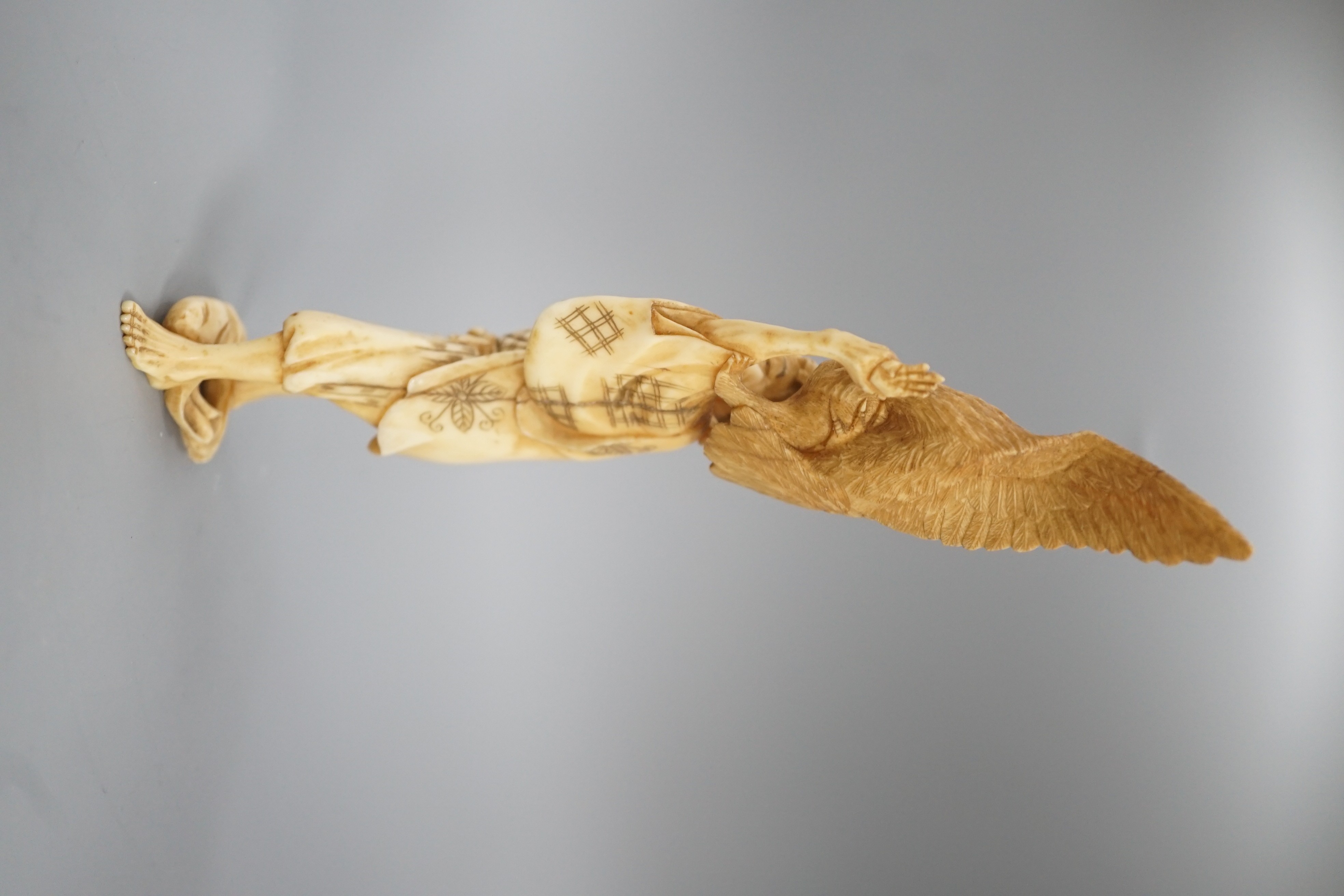 A Japanese ivory okimono of a man holding a monkey which is being attacked by an eagle, early 20th century 15.5cm
